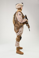 Soldier in US marines uniform with rifle on light grey background, studio shot
