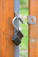 An open lock hangs on the fence door.