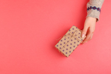 Top view of woman hands holding gift box on pink background