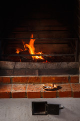 Metal ashtray with cigarette butts on a shelf near the fireplace