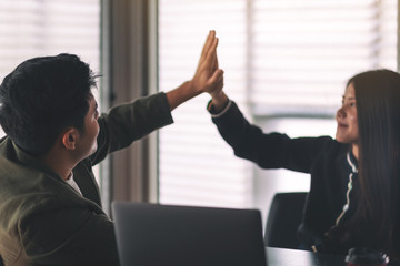 Two businesspeople putting their hands to make high five to each other