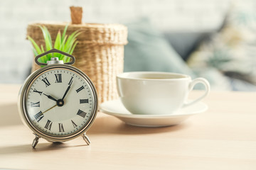 Fototapeta na wymiar Classic vintage alarm clock and coffee cup on wooden background