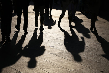 Black silhouettes and shadows of people on the street. Crowd walking down on sidewalk, concept of...