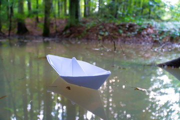 A paper boat sailing in the mountain forest lake. Small Paper Boat. Paper Ship Floating in the Sea. Origami Paper Boat Sailing. Mud water.