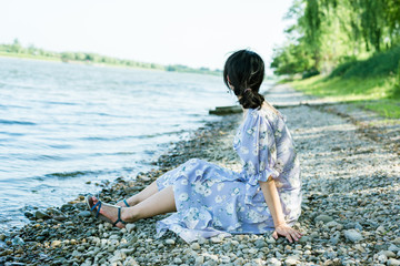Young Asian woman sitting on the river bank, summer time
