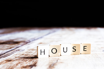 House word made of tiles on dark wooden background