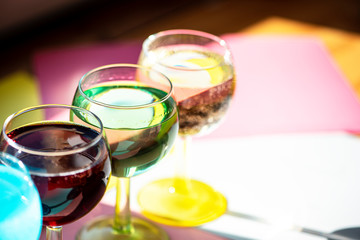 Multi-colored liquor in glasses in the sun on a table.