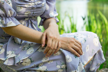 Young woman sitting on the grass. Closeup of hands