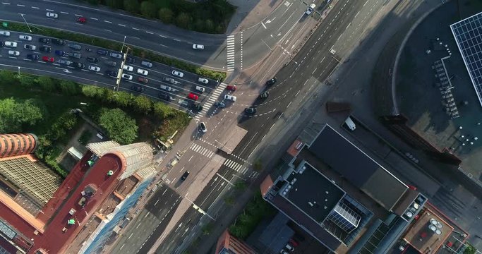 Aerial top down view of junction with cars and traffic at the morning rush hour during summer sunny day. Drone flying above filming straight down and indirect following the street. Helsinki Finland