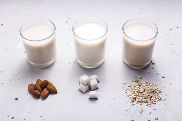 Vegan milk from coconut, oatmeal and almonds on a gray table