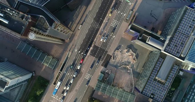 Aerial top down view of junction with cars and traffic at the morning rush hour during summer sunny day. Drone flying filming straight down indirect and panning around the street . Helsinki Finland
