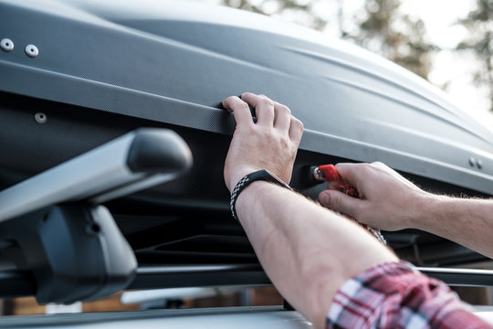 Men's Hands Cover The Assembled, Roomy Trunk Or Cargo Box On The Roof Of The Car, For Safety, Before Leaving For A Family Vacation.