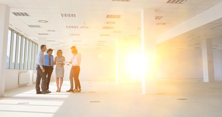 Full length of business colleagues standing while discussing at new office