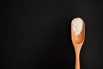 wooden spoon on a black background with salt