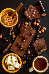 Chocolate bars and nuts on black table background top view