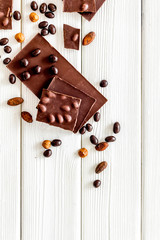 Chocolate bars and nuts on white wooden table background top view mockup
