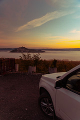 Fototapeta na wymiar car travel concept view of sunrise over city on the top of the hill