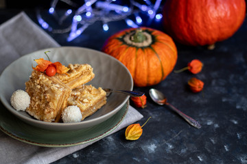 Halloween Pumpkins of bright orange color lie on a dark background, next to red berries. On a gray...