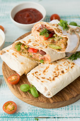 Traditional Mexican food burritos with beans and vegetables. Vegetarian rolls with red beans and vegetables lie on an aged wooden table.