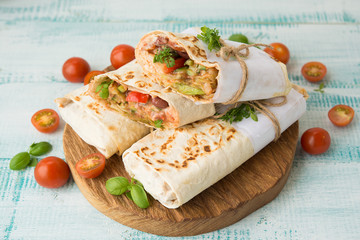 Traditional Mexican food burritos with beans and vegetables. Vegetarian rolls with red beans and vegetables lie on an aged wooden table.