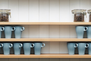 ceramic cups on the shelves in front of white wall.