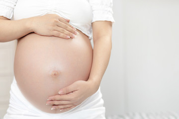 New mom Pregnant woman in white underwear uses hand touch tummy belly with baby. Young woman expecting a baby Stand in the outdoors.