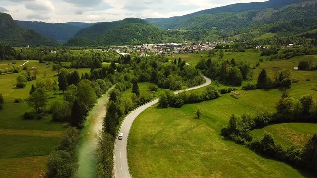 Drone shot of Bohinjska Bistrica, Slovenia, next to a river flowing, surrounded by mountains