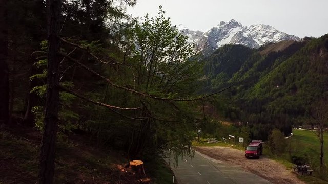 Drone Footage of Red Van Parked on the Side of Road in Slovenian Pine Forest in Zgornje Jezersko Slovenia, Europe with Alps in the Background