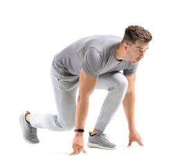 Sporty young man in crouch start position on white background