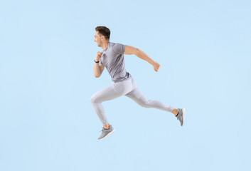 Fototapeta na wymiar Running young man on color background