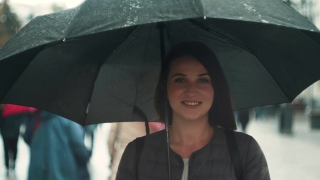 Portrait of smiling woman under umbrella in rain. Tourist girl under umbrella in rain
