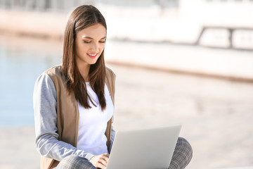Beautiful female student with laptop outdoors