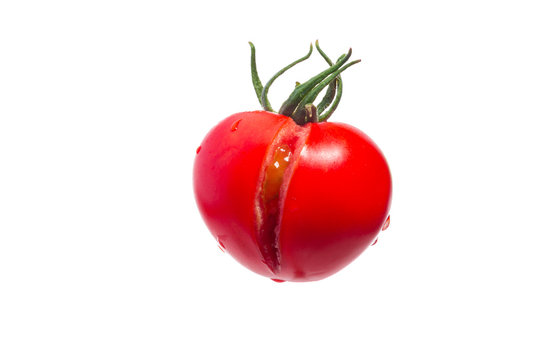 Fresh cracked tomato with green peduncle and drops of water isolated on white background. Symbol of vagina