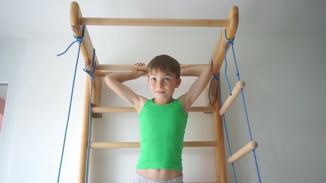 boy does an exercise on the horizontal bar in the children's gym at school