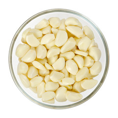 Peeled garlic cloves in glass bowl, from above. Allium sativum, with pungent flavor, used as seasoning or condiment and in medicine. Isolated macro food photo, closeup, on white background.