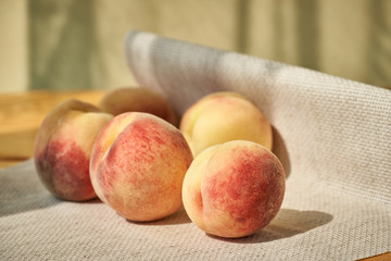 Summer still life with ripe peaches on a linen cloth on a wooden table.