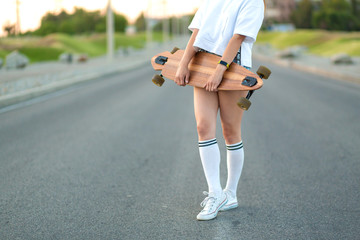 Beautiful sexy young girl in short shorts walking with longboard in sunny weather. Leisure. Healthy lifestyle. Extreme sports. Fashion look, outdoor hipster portrait, Bali, sneakers,hipster,sunse