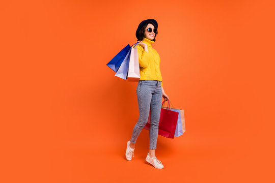 Fulll length body size photo of kind rejoicing overjoyed girl customer who just went out of shopping mall while isolated with orange background
