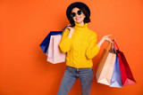 Photo of nice charming girl attractive joyful girl having just ended up shopping and being overjoyed and cheerful while isolated with orange background
