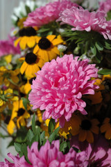 Pink daisies in a bouquet opposite a light background closeup