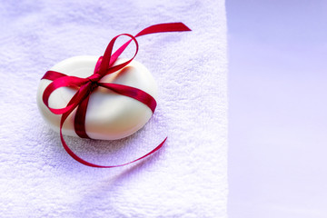 A piece of soap tied with a ribbon tied in a bow, lies on a towel. The concept of cleanliness and pleasant gifts.