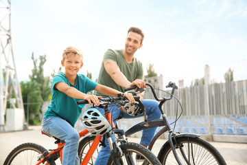 Obraz premium Happy father and son riding bicycles outdoors