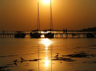 boats and people on the coast beach in the sea sunset sundown sunshine 