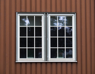 Two white adjacent large windows on a brown wood facade