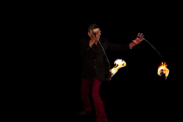 Fototapeta premium Man dominating the fire taking the flames with his chains in motion in Mexico City
