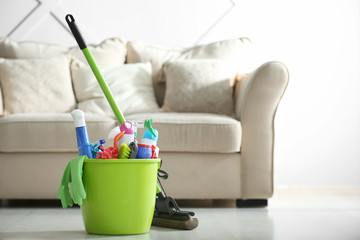 Bucket with cleaning supplies on floor in room