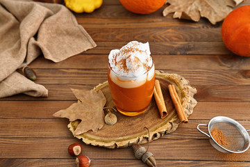 Glass of tasty pumpkin coffee on wooden table