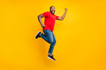 Fototapeta na wymiar Full length body size side profile photo of casual winning rejoicing overjoyed running black man isolated with yellow background