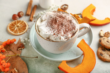 Cup of tasty pumpkin coffee on light background