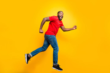 Fototapeta na wymiar Full length body size photo of casual running man who aspires to achieve what he has planned while isolated with yellow background